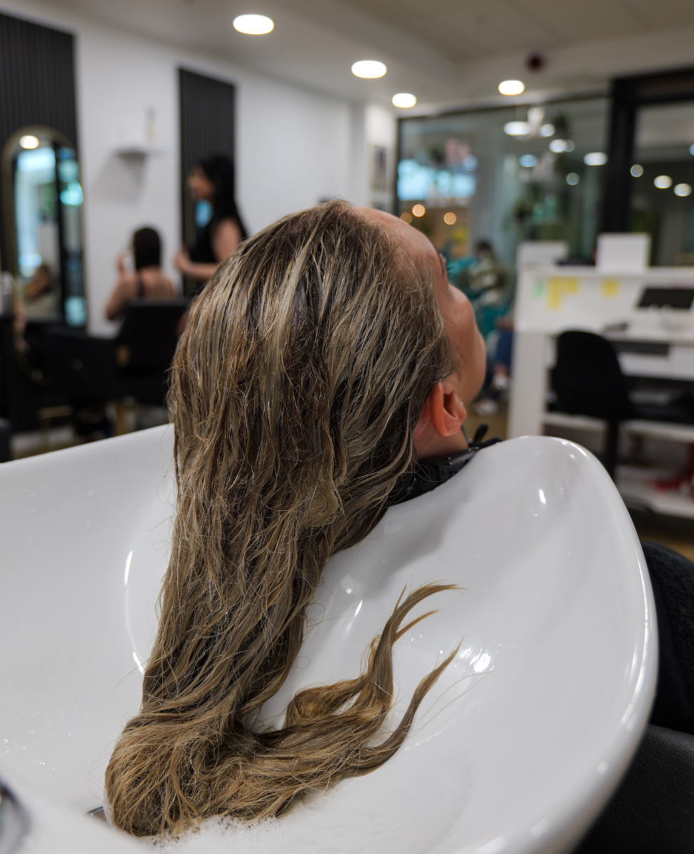 close up of wet blond hair of young blond woman sitting at the hair dresses washing sink having her hair washed